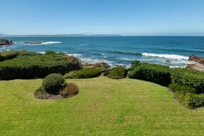 a grassy field with the ocean in the background at Bayview Bliss in Hermanus