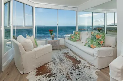 a living room with two white chairs and a large window at Bayview Bliss in Hermanus