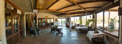 a restaurant with tables and chairs and windows at Damas Guest Farm in Worcester