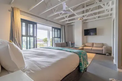 a bedroom with a large bed and a living room at Whale Rock Luxury Lodge in Hermanus