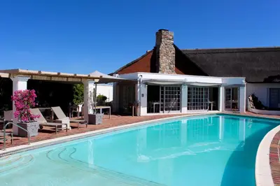 a swimming pool in front of a house at Whale Rock Luxury Lodge in Hermanus
