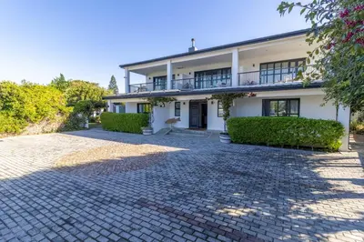 a large white house with a brick driveway at Whale Rock Luxury Lodge in Hermanus