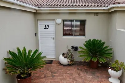 a house with two plants in front of a door at House 10-on-Sea in Hermanus