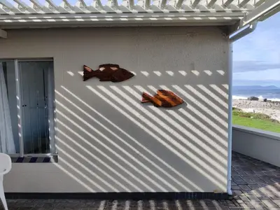 three pieces of art on the side of a building at House 10-on-Sea in Hermanus