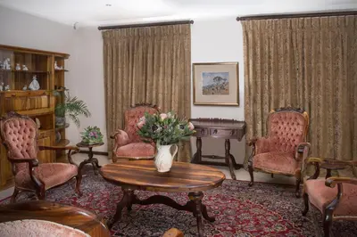 a living room with chairs and a table with a vase of flowers at Blaauwheim Guest House in Somerset West