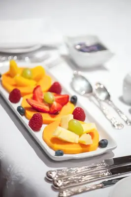 a plate of fruit and berries on a table at Blaauwheim Guest House in Somerset West
