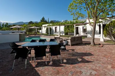 a patio with a table and chairs in front of a house at La Galiniere Guest Cottages in Franschhoek