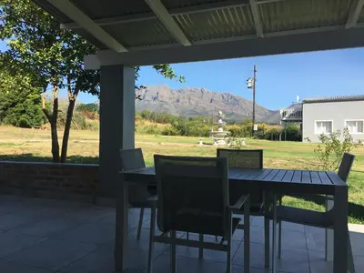 a table and chairs on a patio with mountains in the background at Sweetwater Guesthouse in Wellington