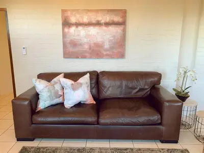 a brown leather couch with two pillows on it at Groenvlei Guest Farm in Kuilsrivier