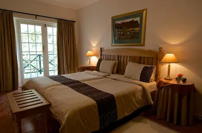a bedroom with a bed with two lamps and a window at Golden Hill Guest House in Somerset West