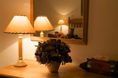 a table with a lamp and a vase with flowers on it at Golden Hill Guest House in Somerset West