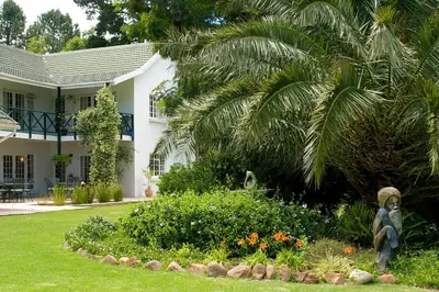 a statue in a garden in front of a house at Golden Hill Guest House in Somerset West