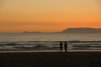 a couple standing on the beach at sunset at Golden Hill Guest House in Somerset West