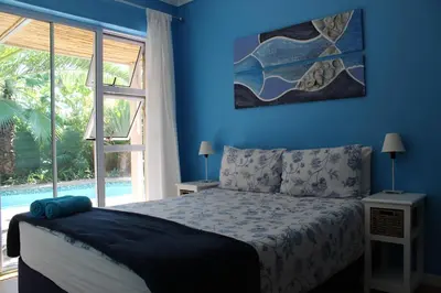 a blue bedroom with a bed and a large window at Elements Cape Town in Table View