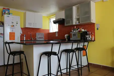 a kitchen with three bar stools at a kitchen counter at Elements Cape Town in Table View