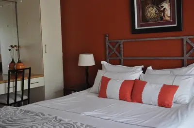 a bedroom with a bed with red and white pillows at Pelican Place Guest Cottages in Durbanville
