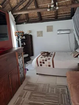 a bedroom with a bed and a dresser in it at Pelican Place Guest Cottages in Durbanville