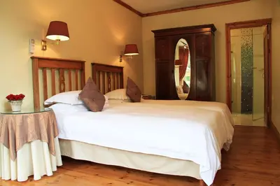 a bedroom with a large white bed and a table at Evergreen Lodge in Stellenbosch