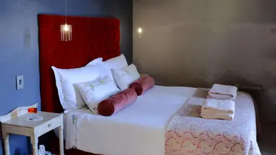 a bedroom with a white bed with a red headboard at Kuruma Farm Cottages in Worcester