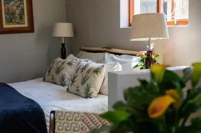 a room with a bed with pillows and a lamp at Kuruma Farm Cottages in Worcester