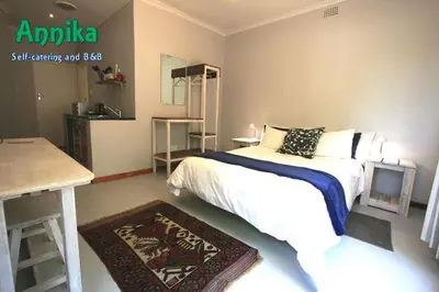 a bedroom with a bed and a table with a television at Annika Self-catering and B&B in Stellenbosch