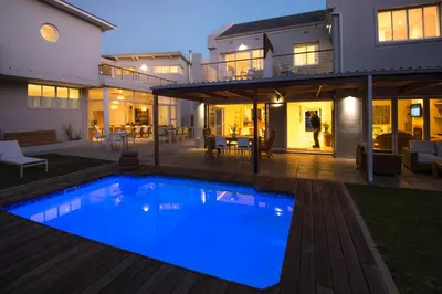 a house with a large swimming pool in the backyard at Bamboo Guest House in Hermanus