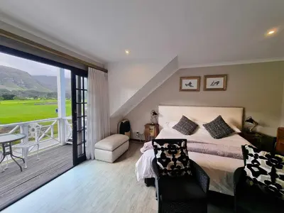 a bedroom with a large bed and a balcony at Mulligans Guest Lodge in Hermanus