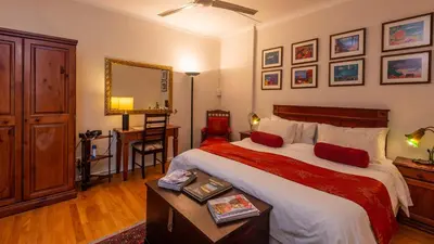 a bedroom with a large bed with a table and a desk at Brown Jug Guest House in Hermanus