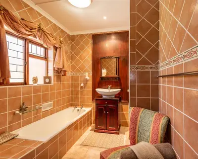 a bathroom with a bath tub and a sink at Brown Jug Guest House in Hermanus