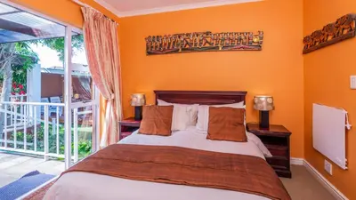 a bedroom with a bed with orange walls at Brown Jug Guest House in Hermanus