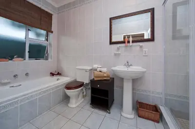 a bathroom with a sink and a toilet and a bath tub at Brown Jug Guest House in Hermanus