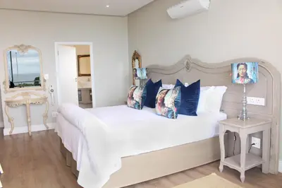 a bedroom with a large white bed with blue pillows at Hermanus Boutique Guest House in Hermanus