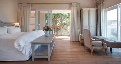 a bedroom with a large bed and a table and chairs at Hermanus Boutique Guest House in Hermanus