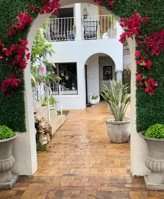 an arched walkway with pink flowers and plants at Welgemoed Villa in Bellville
