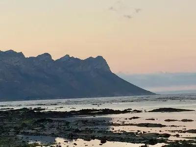 a view of the ocean with a mountain in the background at False Bay Inn in Strand
