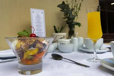 a table with a bowl of food and a glass of juice at Lemoenkloof Boutique Hotel in Paarl