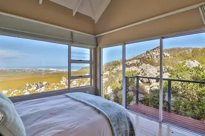 a bedroom with a bed and large windows at Tranquility Heights in Pringle Bay