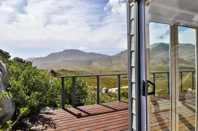a room with a balcony with a view of mountains at Tranquility Heights in Pringle Bay