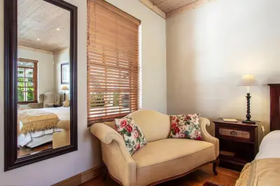 a bedroom with a mirror and a chair and a bed at De Hoek Manor in Stellenbosch