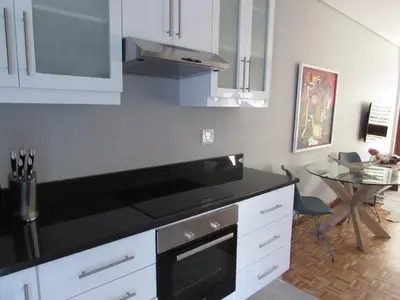 a kitchen with white cabinets and a black counter top at Live Like a Local: Studio 29 @ 25 Market street in Stellenbosch