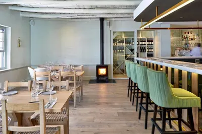 a restaurant with wooden tables and chairs and a fireplace at Le Quartier Francais in Franschhoek