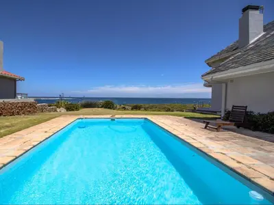 a swimming pool with a view of the ocean at Sandbaai Country House in Hermanus