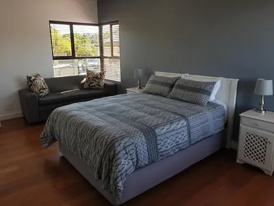a bedroom with a bed and a couch and a window at Modern spacious home in heart of Cape Winelands in Somerset West