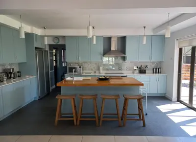 a kitchen with blue cabinets and a large island with stools at Modern spacious home in heart of Cape Winelands in Somerset West