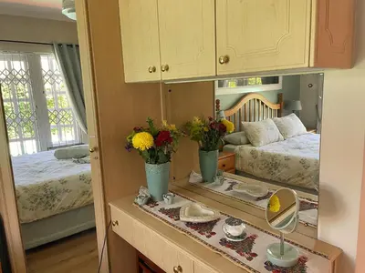 a bedroom with two beds and a mirror at Lemon Tree Cottage in Edgemead