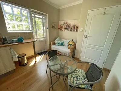 a room with a table and chairs and a window at Lemon Tree Cottage in Edgemead