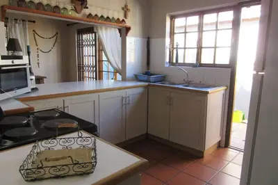 a kitchen with white cabinets and a stove top oven at Getaway on Peck Way in Edgemead