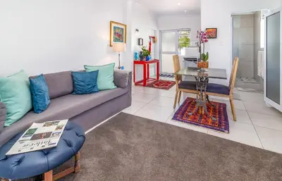a living room with a couch and a table at Bleu Cobalt Cottage in Franschhoek
