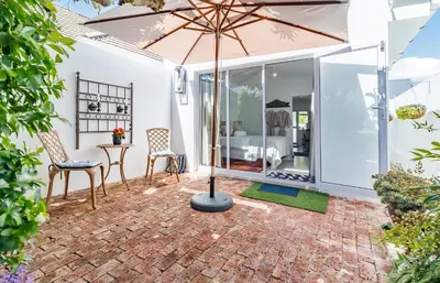 a patio with an umbrella and a table and chairs at Bleu Cobalt Cottage in Franschhoek