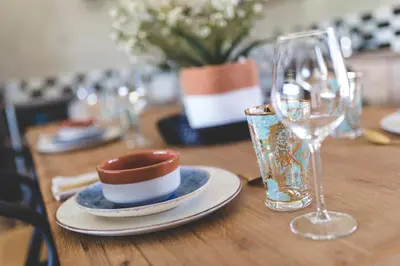 a wooden table with a plate and a wine glass at The Farmstead in Franschhoek